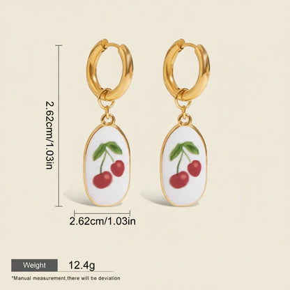 Seraphina Treasures gold hoop earrings with white oval pendants featuring red cherries and green leaves. Waterproof and hypoallergenic.