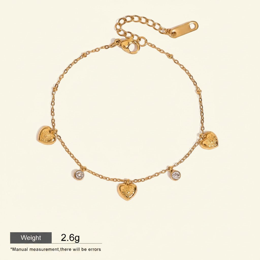 Seraphina Treasures gold-tone bracelet with delicate chain, featuring five heart charms and three sparkling zirconia stones. Adjustable length.