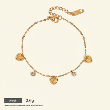 Seraphina Treasures gold-tone bracelet with delicate chain, featuring five heart charms and three sparkling zirconia stones. Adjustable length.