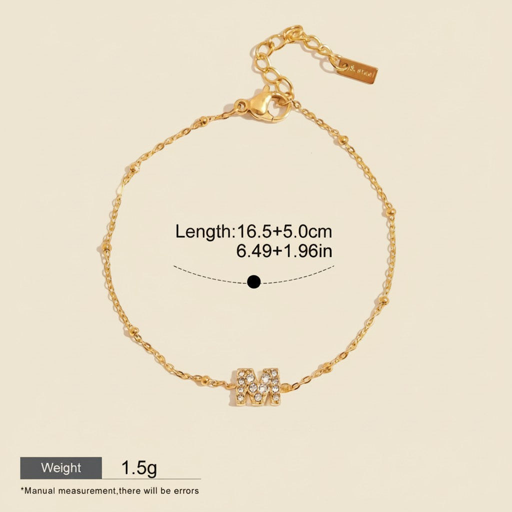 Seraphina Treasures gold-tone bracelet with cubic zirconia 'M' charm and beaded chain. Adjustable length.